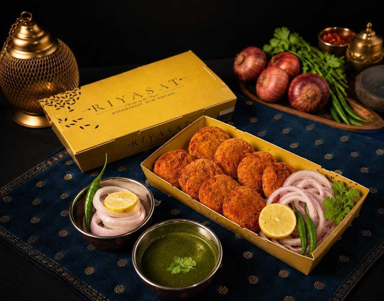 A lit brass lantern, rose petals and whole spices arranged on indigo brocade